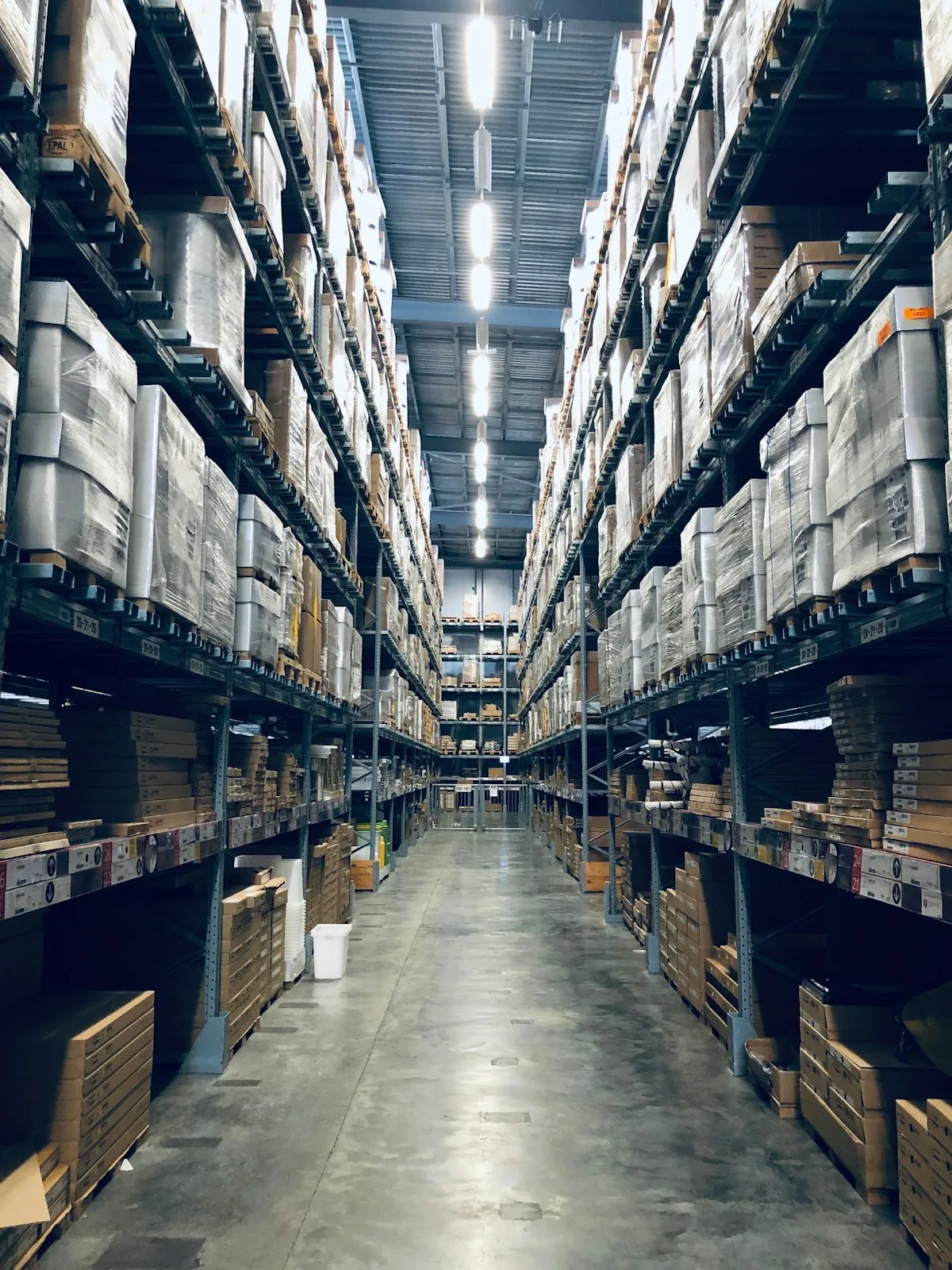Allée d'entrepôt logistique avec racks de stockage et cartons